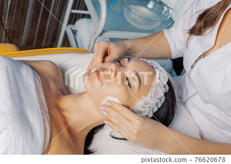 Professional beautician woman wipes face with Professional beautician woman wipes face with 76620678