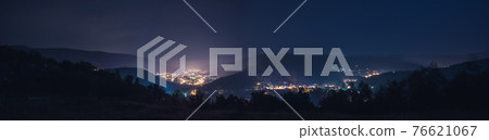 A small glowing city with houses surrounded by mountains 76621067