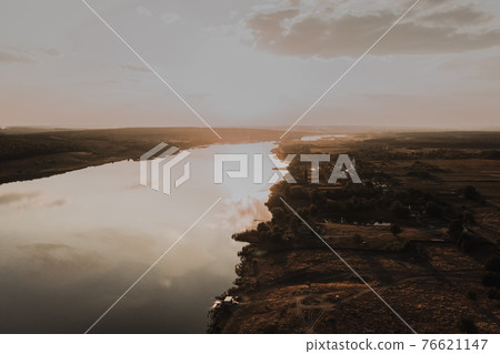 a small village with small houses near a wide, clean, calm river 76621147