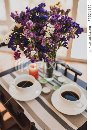 Two cups of coffee and bouquet of purple pink flowers in a vase Two cups of coffee and bouquet of purple pink flowers in a vase 76621152