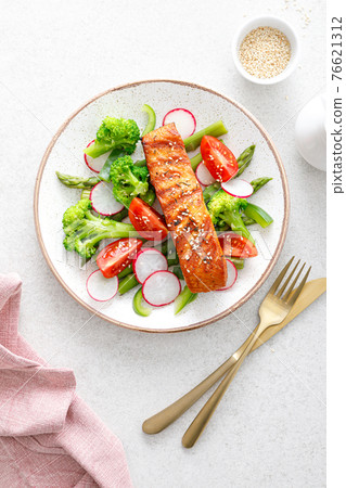 Salmon fish fillet grilled and vegetable salad with radish, tomato, green pepper, broccoli and asparagus. 76621312