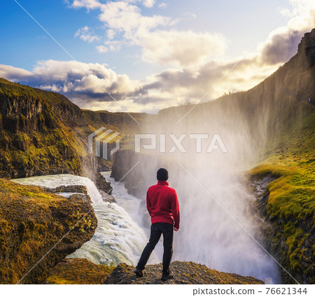 Young hiker standing at the edge of the Gullfoss waterfall in Iceland Young hiker standing at the edge of the Gullfoss waterfall in Iceland 76621344