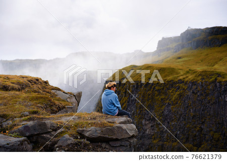 Hiker sitting at the edge of the Gullfoss waterfall in Iceland Hiker sitting at the edge of the Gullfoss waterfall in Iceland 76621379