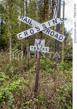 Old sign of railroad crossing on spring trees background Old sign of railroad crossing on spring trees background 76622643