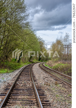 Curve of rail road pathways leading to a city Curve of rail road pathways leading to a city 76622647