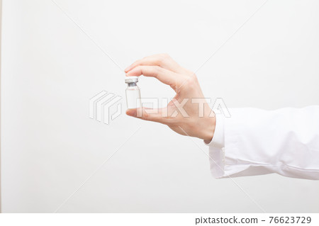 Vaccine in a glass bottle held in the hand, liquid medicine Vaccine in a glass bottle held in the hand, liquid medicine 76623729
