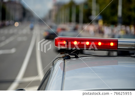 MINSK. BELARUS - JULY 2016: Red flashing lights on a police car against the background of a road and a crowd of people. 76625955