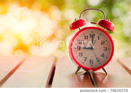 9 o'clock Classic Alarm Clock  on Wood Table with Sun Light green background. 76626559