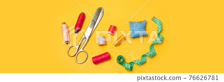 Multi-colored thread spools and sewing accessories on a yellow background. Multi-colored thread spools and sewing accessories on a yellow background. 76626781