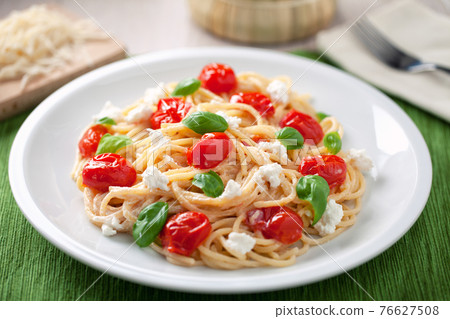 Spaghetti with cherry tomatoes and fresh ricotta on a plate. 76627508