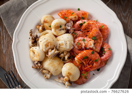 Grilled prawns and cuttlefish on a plate. High quality photo. Grilled prawns and cuttlefish on a plate. High quality photo. 76627626