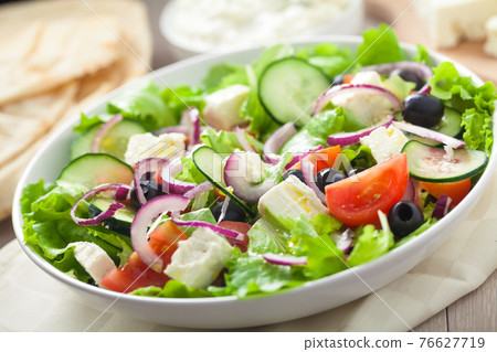 Greek salad with tomatoes, feta, olives and cucumbers. 76627719