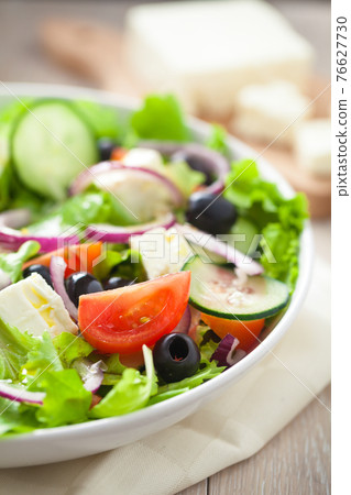 Greek salad with tomatoes, feta, olives and cucumbers. 76627730