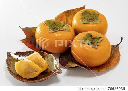Persimmons lined up on red-colored leaves Persimmons lined up on red-colored leaves 76627986