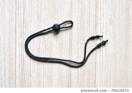 black eyeglasses strap with adjustable button accessory for glasses on a wooden background black eyeglasses strap with adjustable button accessory for glasses on a wooden background 76628470