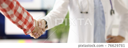 Doctor with stethoscope around neck shaking patients hand in clinic closeup 76629781