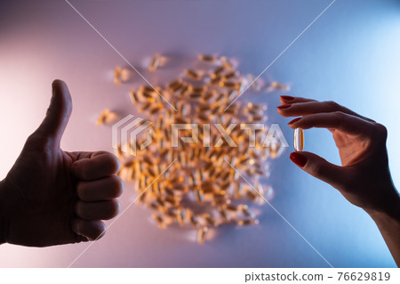 like gesture and hand holding fish oil capsule omega 3 on purple background 76629819