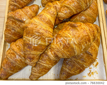 Close up photo of puffy butter croissants in wooden tray Close up photo of puffy butter croissants in wooden tray 76630042