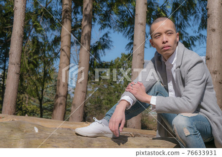 A slender man with a shaven sitting on a stump A slender man with a shaven sitting on a stump 76633931