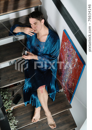 Transgender smoking a cigarette at home 76634146