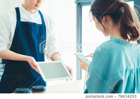A woman preparing for smartphone payment at the checkout at the cash register 76634203