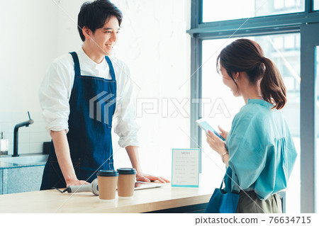 A woman preparing for smartphone payment at the checkout at the cash register 76634715