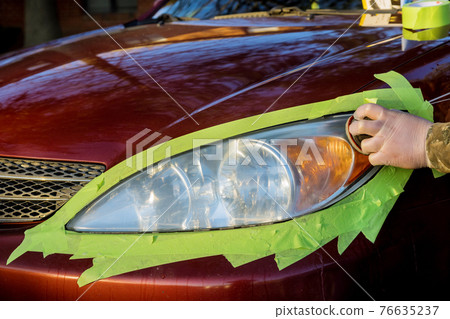 Headlight restore in the worker polishes optics of headlights of the car with the hand tool Headlight restore in the worker polishes optics of headlights of the car with the hand tool 76635237