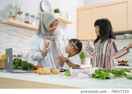 lovely asian woman with daughter and son cooking dinner during ramadan 76637339