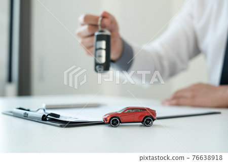 Car dealer businessman holding a car key. Car loan and insurance concept 76638918