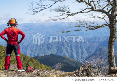 一名男性林業工人站起來看著要維護的山脈 一名男性林業工人站起來看著要維護的山脈 76638920