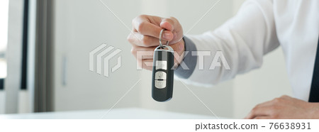 Car dealer businessman holding a car key. Car loan and insurance concept 76638931