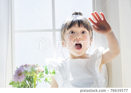 Girl with flowers by the windowsill 76639577