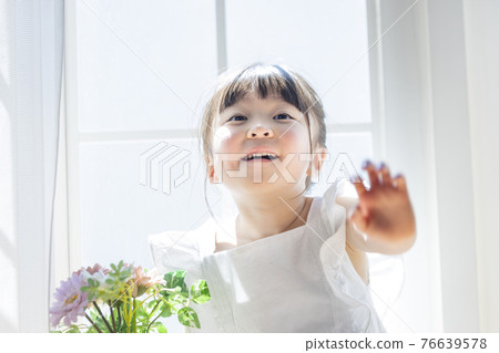 Girl with flowers by the windowsill 76639578