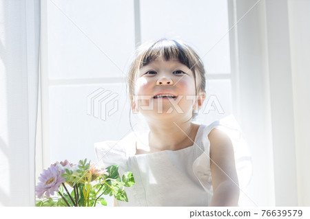 Girl with flowers by the windowsill 76639579