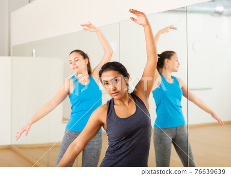 Hispanic woman practicing classic dance moves during group class 76639639