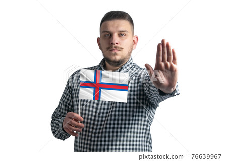 White guy holding a flag of Faroe Islands and with a serious face shows a hand stop sign isolated on a white background White guy holding a flag of Faroe Islands and with a serious face shows a hand stop sign isolated on a white background 76639967
