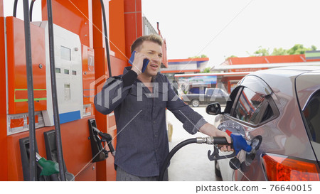 A Caucasian man, people, busy customer filling up fuel by using petrol pump at gasoline petrol station, self service, talking on phone, refuel petroleum oil and energy vehicle business service 76640015