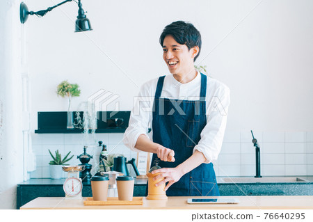 Male cafe staff grinding coffee beans Male cafe staff grinding coffee beans 76640295