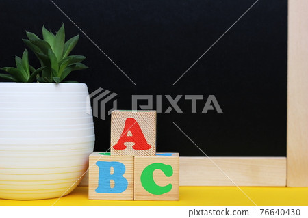 ABC blocks next to a blackboard and a potted houseplant. Back to school. English for beginners. Empty space for text. ABC blocks next to a blackboard and a potted houseplant. Back to school. English for beginners. Empty space for text. 76640430