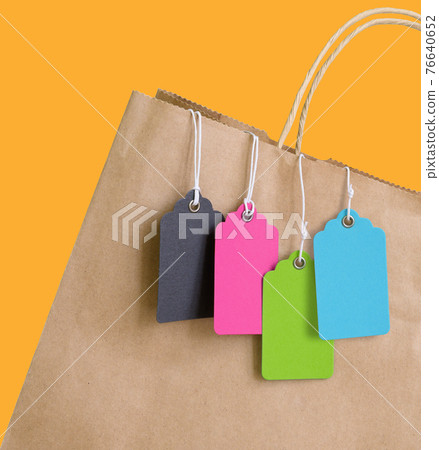 Colorful price tags with rope hanging out of brown shopping bag. 76640652