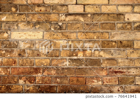 Aged partially crumbled brown brick wall background 76641941