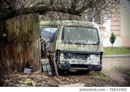 Old broken rusty van near wooden building under leafless tree Old broken rusty van near wooden building under leafless tree 76641982