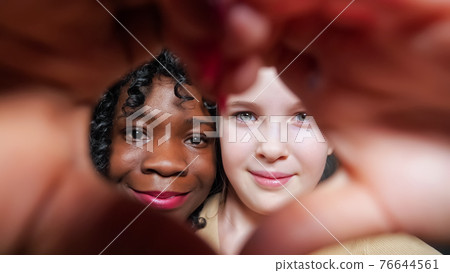 Stepmother and adopted schoolgirl show heart sign with hands 76644561