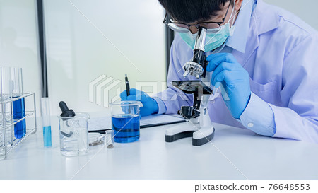 Medical or scientific researcher or man doctor looking at a test tube of clear solution in a laboratory Medical or scientific researcher or man doctor looking at a test tube of clear solution in a laboratory 76648553