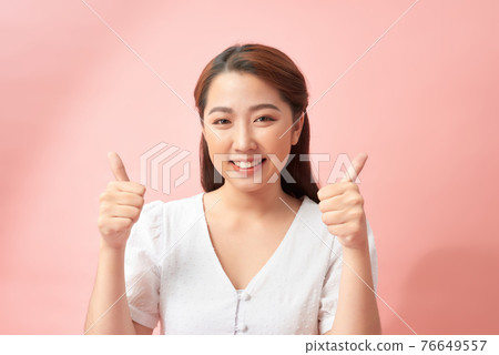 Happy young woman giving thumbs up on pink background Happy young woman giving thumbs up on pink background 76649557