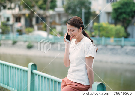 Happy positive young woman chatting on cell outdoors and getting good news. 76649569