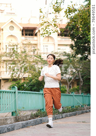Healthy woman are running in the park in the morning. She smiled and enjoyed. 76649581