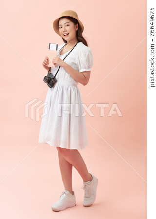 Smiling young beautiful Asian tourist woman holding passport isolated on pink studio background 76649625
