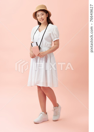 Fun travel portrait of smiling young beautiful Asian tourist woman holding passport isolated on pink background 76649627