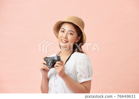 pretty cool young woman model with retro film camera wearing a elegant hat over pink background 76649631